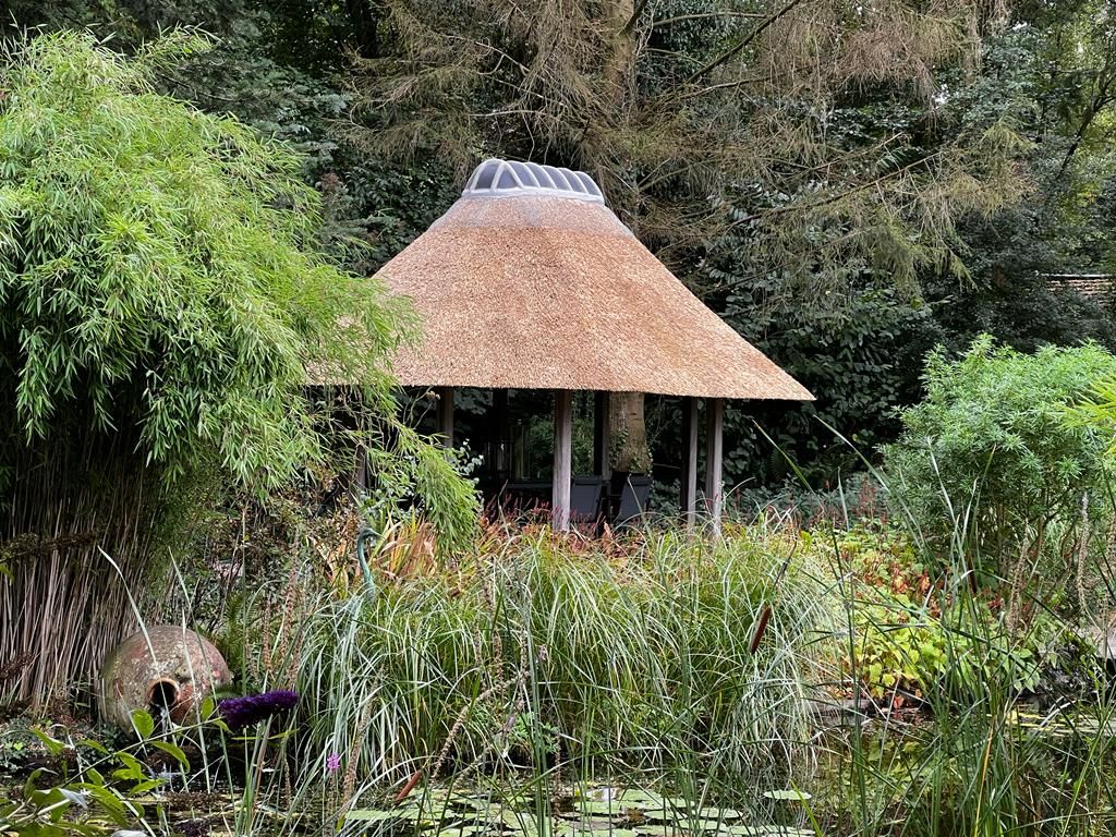 Rond rieten prieel in een weelderige tuin