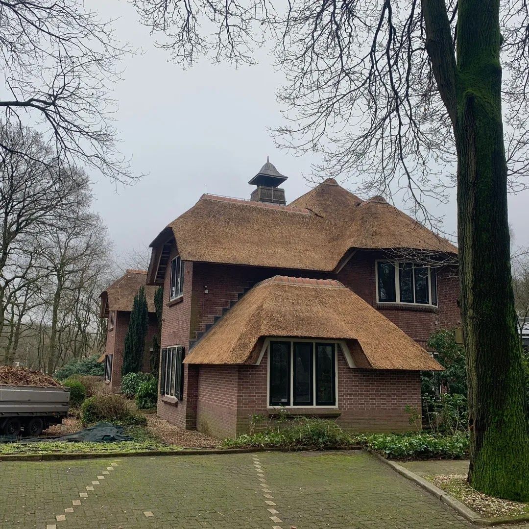 Bakstenen villa met een rieten dak en een rieten schoorsteenkap